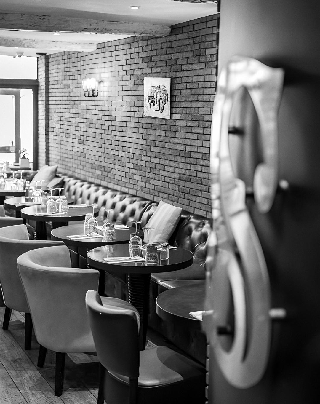 La salle du Scotch : mur de briques, banquette capitonnée, fauteuils en velours et la poignée en S de la porte